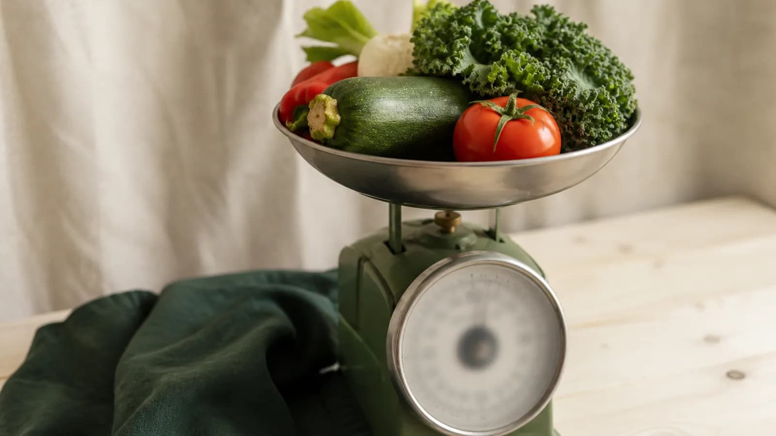 Légumes posés sur une balance de cuisine analogique, illustration du coût énergétique d’un kilo.